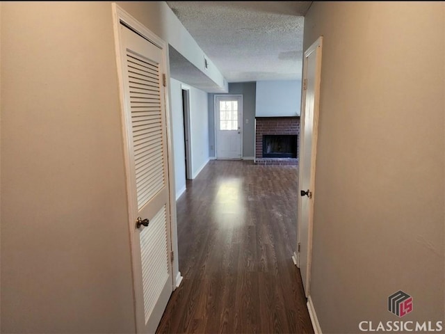 hall with dark wood-type flooring and a textured ceiling