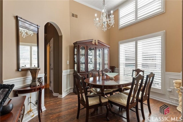 dining space with dark wood-type flooring, ornamental molding, and a chandelier