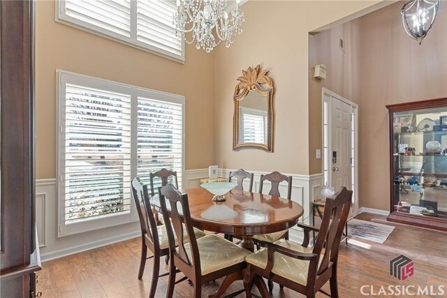 dining room featuring a notable chandelier, hardwood / wood-style flooring, and a high ceiling