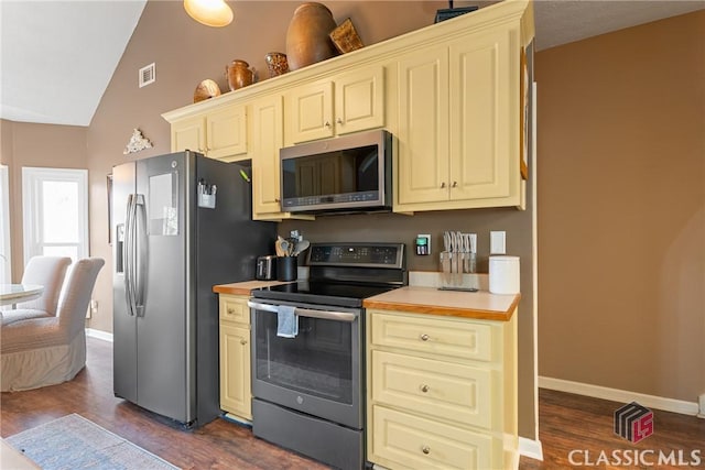 kitchen featuring dark hardwood / wood-style flooring, vaulted ceiling, and appliances with stainless steel finishes