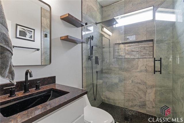 bathroom featuring vanity, toilet, and a shower with door