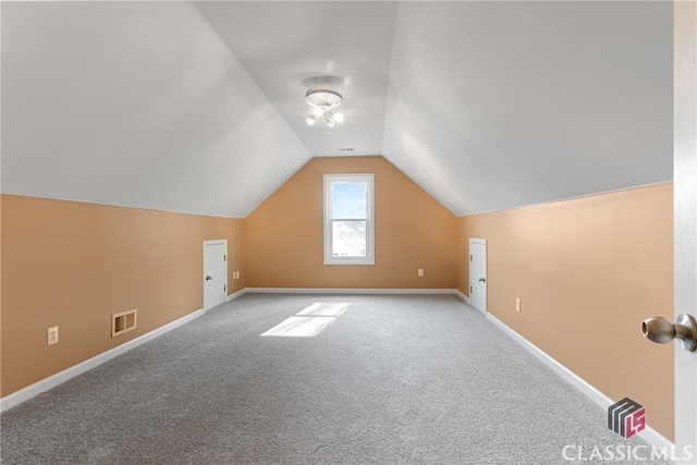 additional living space featuring vaulted ceiling and light colored carpet