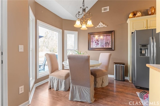 dining room with lofted ceiling, hardwood / wood-style floors, and a notable chandelier