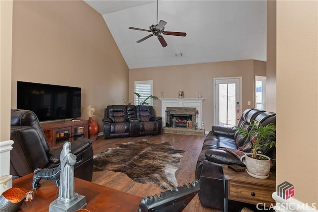 living room with hardwood / wood-style floors, a stone fireplace, high vaulted ceiling, and ceiling fan