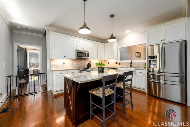 kitchen featuring stainless steel appliances, a kitchen island, a breakfast bar area, and white cabinets