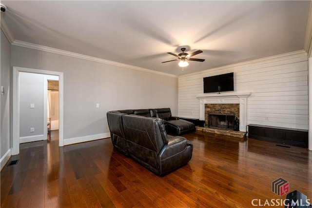 living room with a stone fireplace, dark wood-type flooring, ornamental molding, and ceiling fan