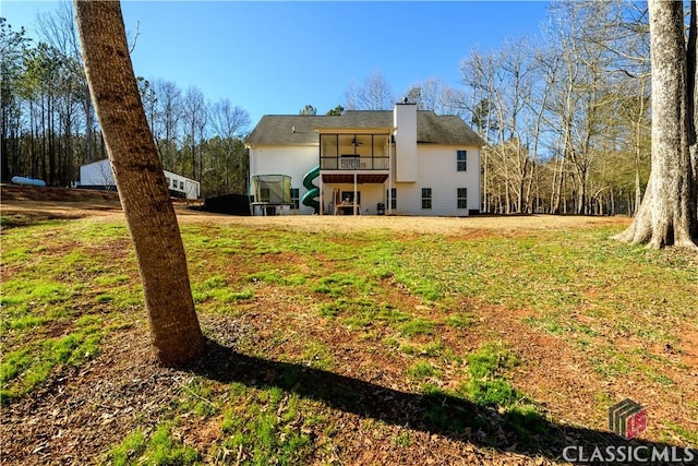 rear view of house with a lawn and a sunroom