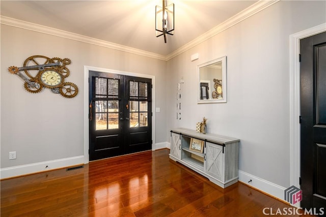 foyer featuring ornamental molding, dark wood-type flooring, a notable chandelier, and french doors