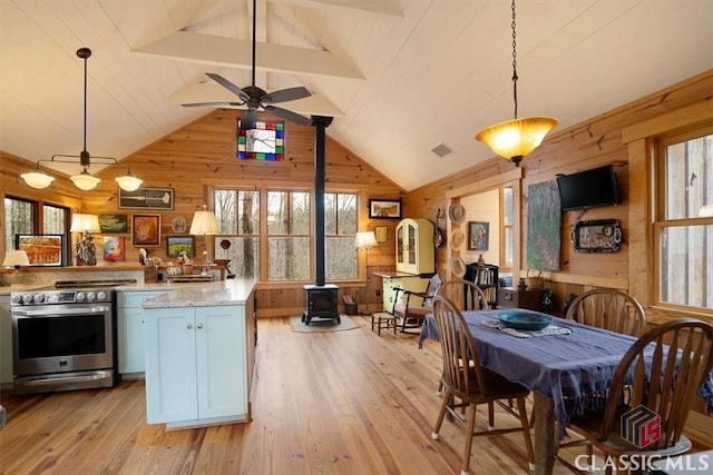 kitchen featuring wood walls, light stone counters, decorative light fixtures, electric range, and a wood stove