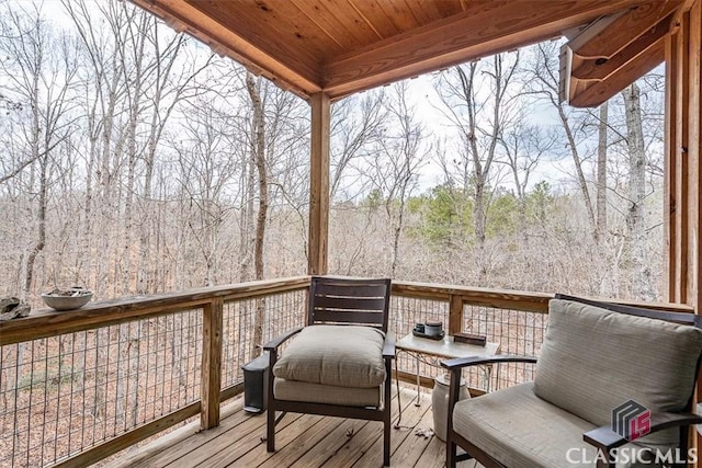 wooden terrace featuring a wooded view and outdoor lounge area