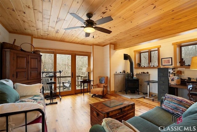 living area with wood-type flooring, a wood stove, and wood ceiling