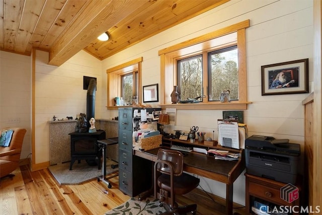 home office featuring light wood-style flooring, beam ceiling, wood walls, wood ceiling, and a wood stove
