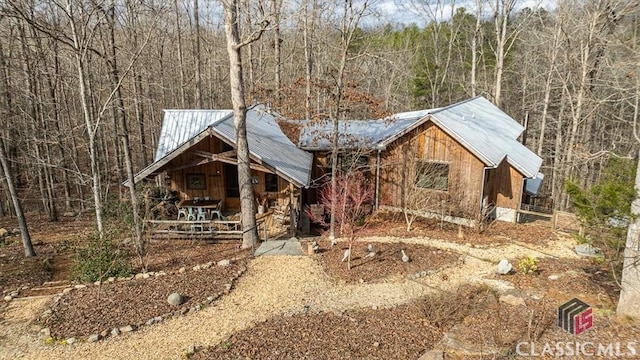 chalet / cabin featuring a porch, a forest view, and metal roof