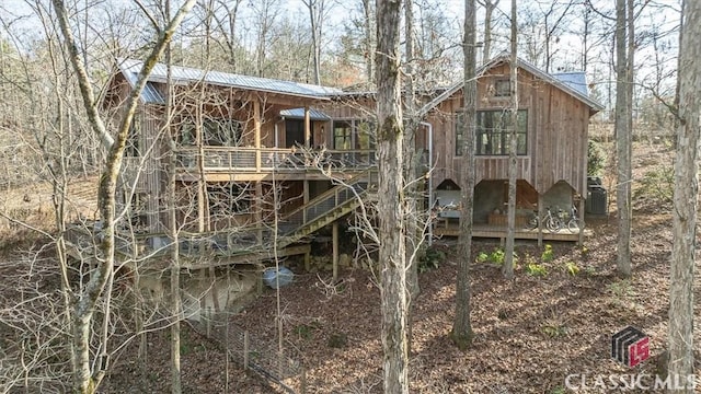 exterior space with a wooden deck, central air condition unit, and metal roof