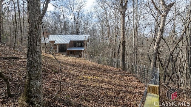 exterior space featuring a forest view and fence