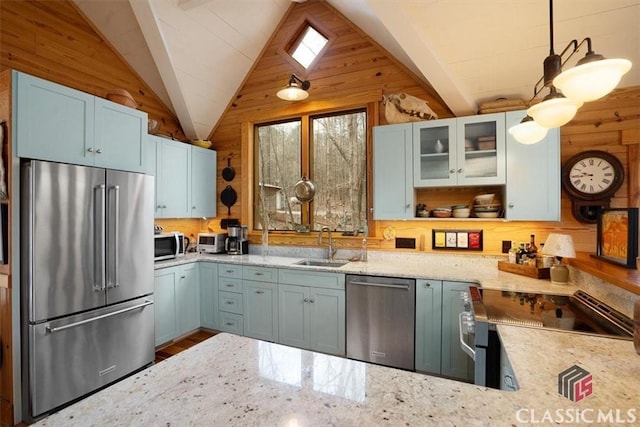 kitchen with wood walls, appliances with stainless steel finishes, lofted ceiling, and light stone countertops