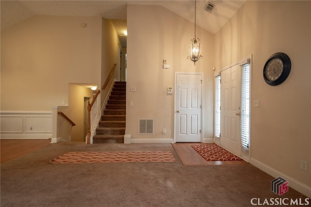 carpeted foyer entrance featuring an inviting chandelier and high vaulted ceiling