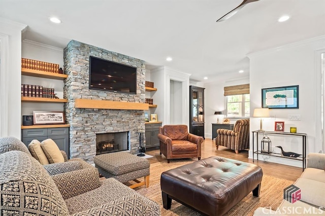 living room featuring crown molding, a fireplace, and light hardwood / wood-style flooring