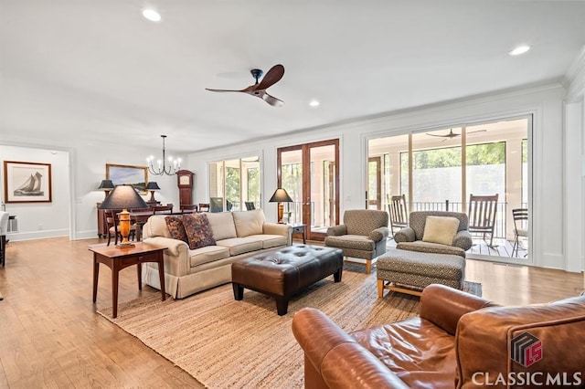 living room with ornamental molding, ceiling fan with notable chandelier, and light hardwood / wood-style floors