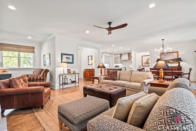 living room featuring crown molding, ceiling fan with notable chandelier, and light hardwood / wood-style flooring