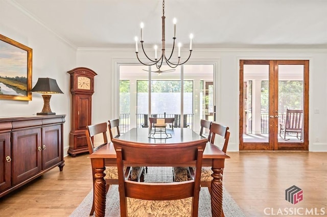 dining room with ornamental molding, french doors, a chandelier, and light wood-type flooring