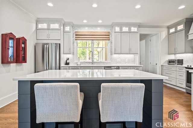 kitchen featuring tasteful backsplash, ornamental molding, stainless steel appliances, and a spacious island