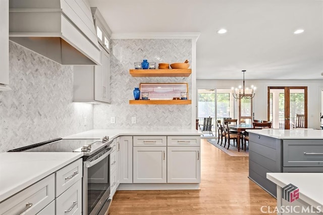 kitchen with white cabinetry, electric range, decorative light fixtures, and crown molding