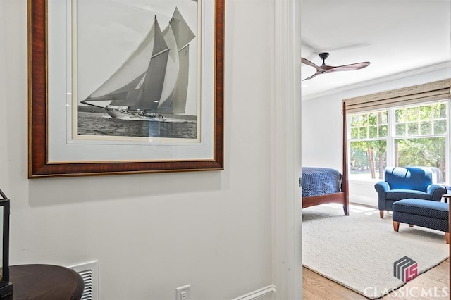 interior space with hardwood / wood-style floors, ornamental molding, and ceiling fan