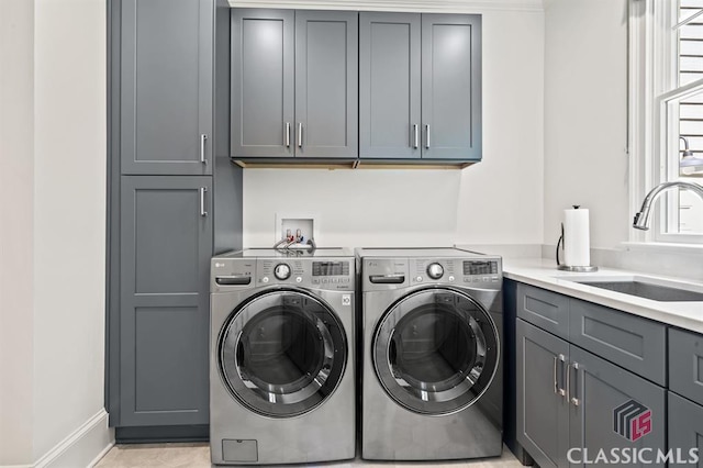 washroom featuring independent washer and dryer, cabinets, and sink