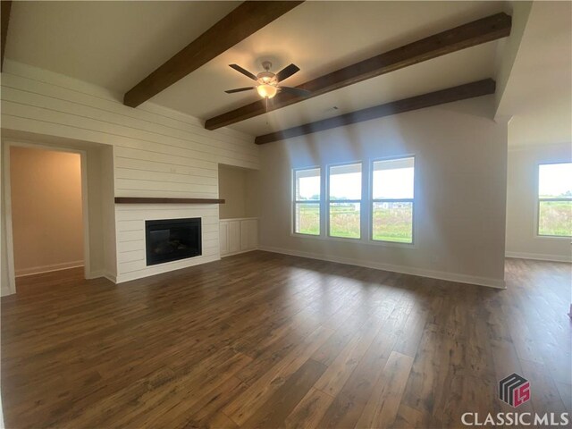 216 Montview Dr, Jefferson, GA 30549 - unfurnished living room featuring a ceiling fan, baseboards, dark wood-type flooring, a large fireplace, and beam ceiling
