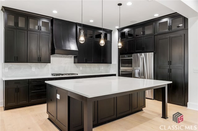 kitchen featuring light hardwood / wood-style flooring, hanging light fixtures, stainless steel appliances, custom range hood, and a center island