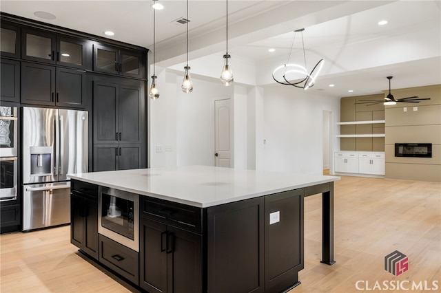 kitchen with a center island, stainless steel appliances, light hardwood / wood-style flooring, decorative light fixtures, and ceiling fan