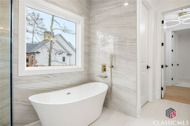 bathroom featuring a bath and tile walls