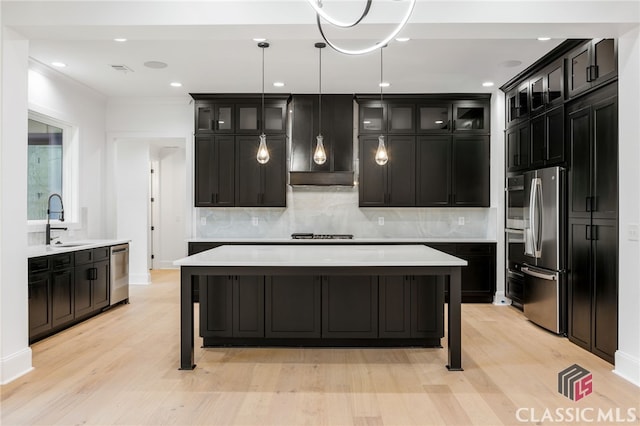 kitchen with decorative light fixtures, stainless steel appliances, a kitchen bar, and a center island