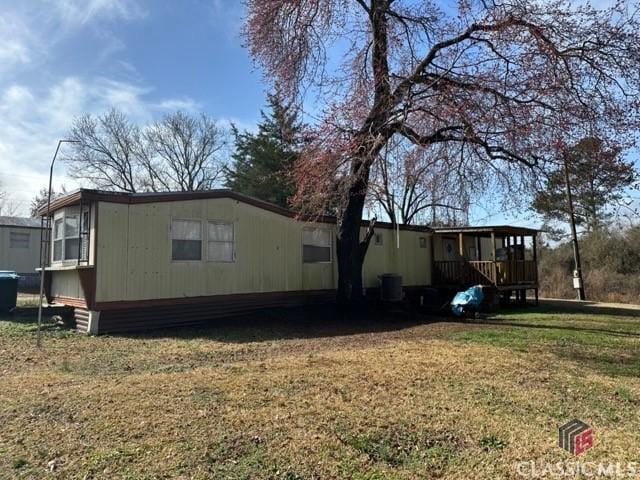 rear view of property with a yard and central air condition unit