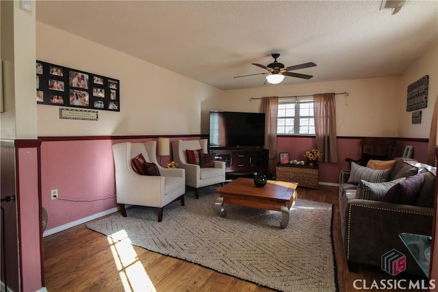 living room featuring ceiling fan, a textured ceiling, and hardwood / wood-style floors