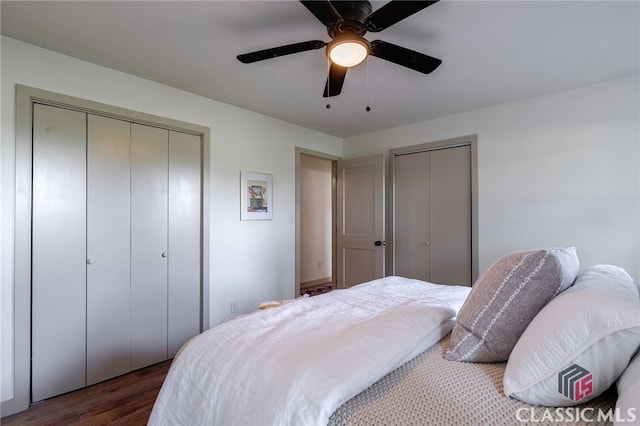 bedroom featuring ceiling fan, dark hardwood / wood-style floors, and two closets