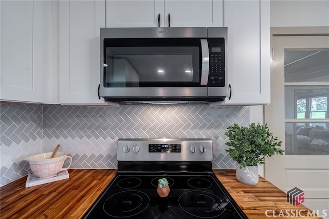 kitchen featuring white cabinetry, appliances with stainless steel finishes, butcher block countertops, and backsplash