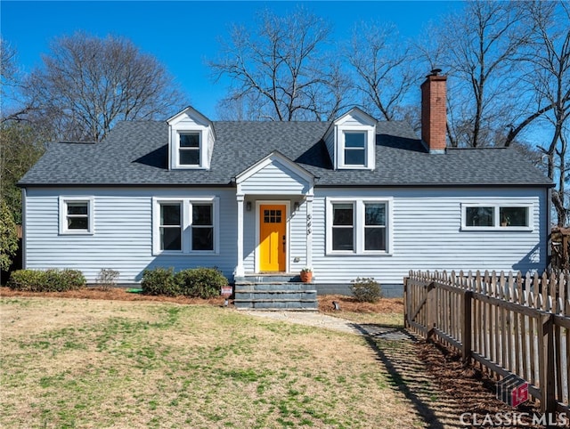 cape cod home featuring entry steps, a shingled roof, a chimney, fence, and a front lawn