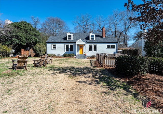 rear view of property with entry steps, a shingled roof, a fire pit, a lawn, and a chimney