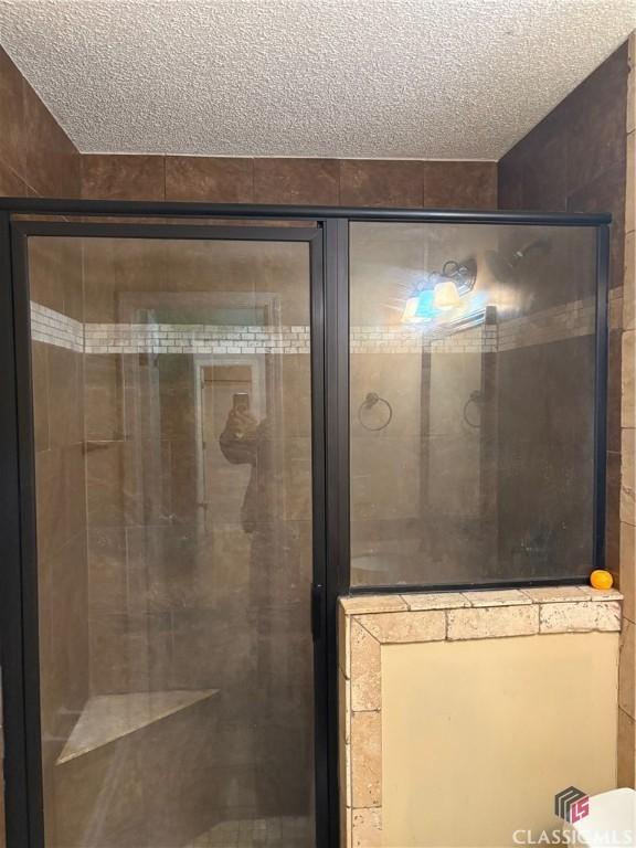 bathroom with a textured ceiling and walk in shower