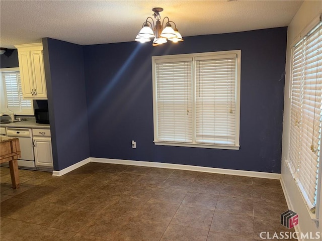 unfurnished dining area featuring sink, dark tile patterned flooring, a textured ceiling, and a notable chandelier