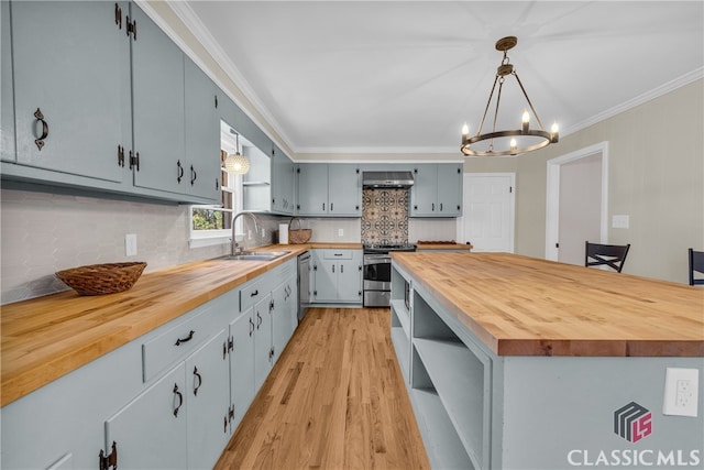 kitchen featuring stainless steel appliances, butcher block counters, a sink, open shelves, and pendant lighting