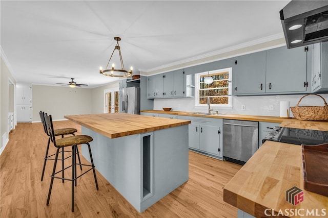 kitchen featuring wood counters, appliances with stainless steel finishes, pendant lighting, and crown molding