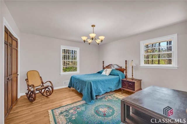 bedroom with light wood-style flooring, multiple windows, visible vents, and a notable chandelier