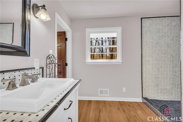 full bath with vanity, wood finished floors, visible vents, and baseboards