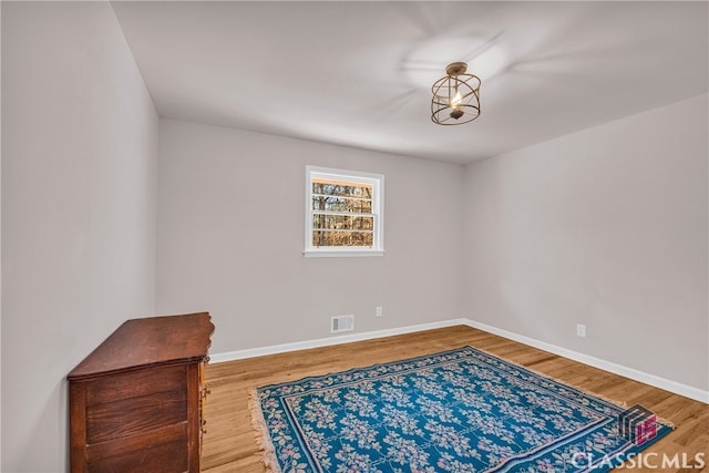 empty room with wood finished floors, visible vents, and baseboards