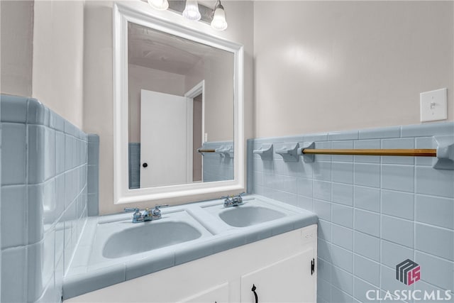 bathroom with double vanity, wainscoting, a sink, and tile walls