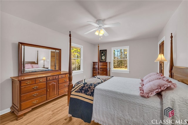 bedroom featuring a ceiling fan, multiple windows, light wood-style flooring, and baseboards