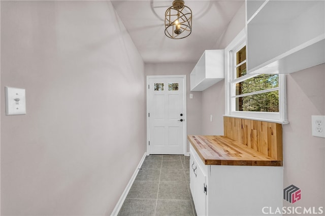 doorway with tile patterned flooring and baseboards